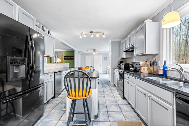 kitchen featuring a ceiling fan, a sink, under cabinet range hood, black appliances, and backsplash