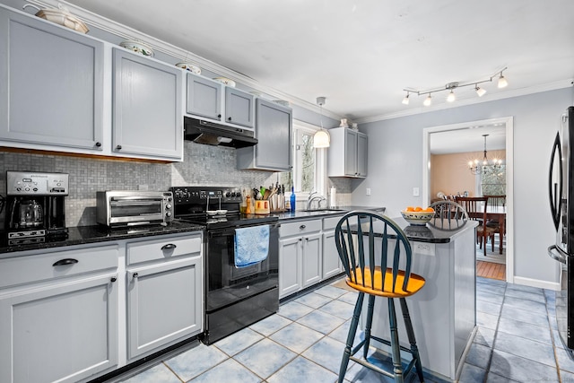 kitchen featuring a toaster, tasteful backsplash, black electric range oven, under cabinet range hood, and a chandelier