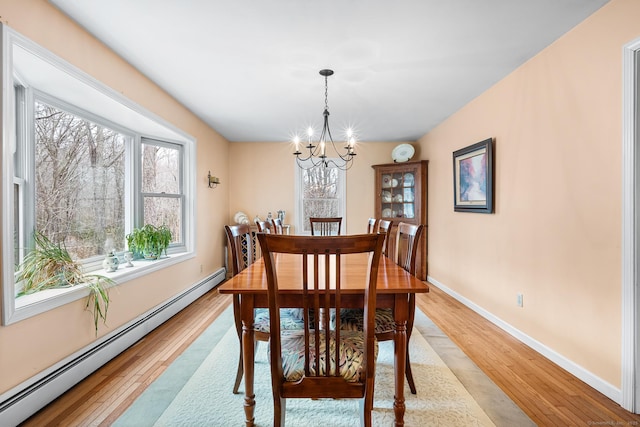 dining space featuring light wood-style floors, baseboards, a baseboard heating unit, and an inviting chandelier