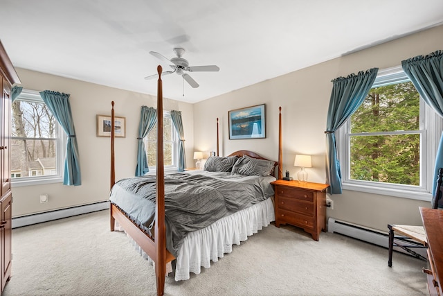 bedroom featuring a baseboard heating unit, multiple windows, light carpet, and a ceiling fan