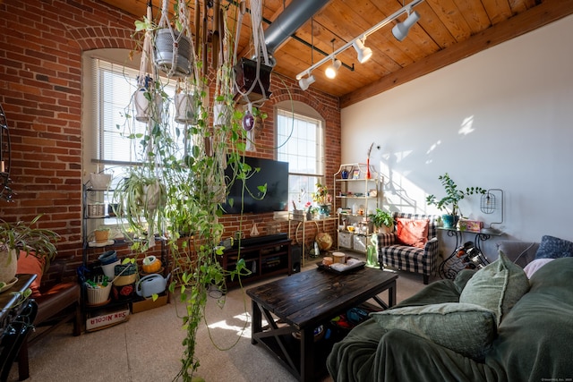 living area with wooden ceiling, rail lighting, and brick wall