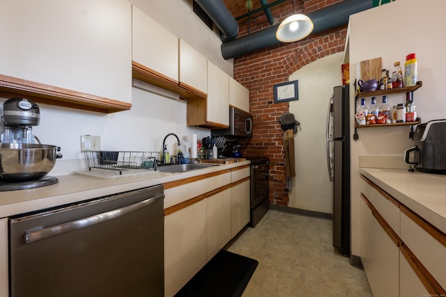 kitchen featuring brick wall, light countertops, appliances with stainless steel finishes, white cabinetry, and a sink