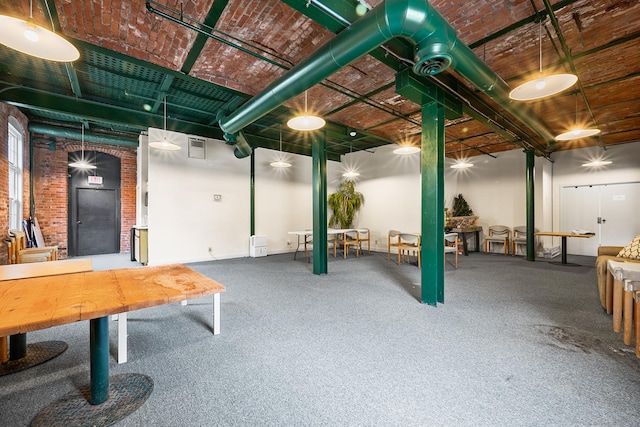 below grade area featuring carpet flooring, visible vents, and brick wall