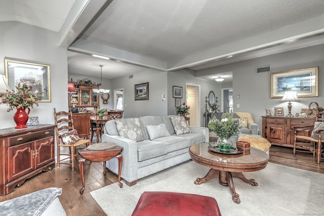 living area featuring wood-type flooring, visible vents, a notable chandelier, and a textured ceiling