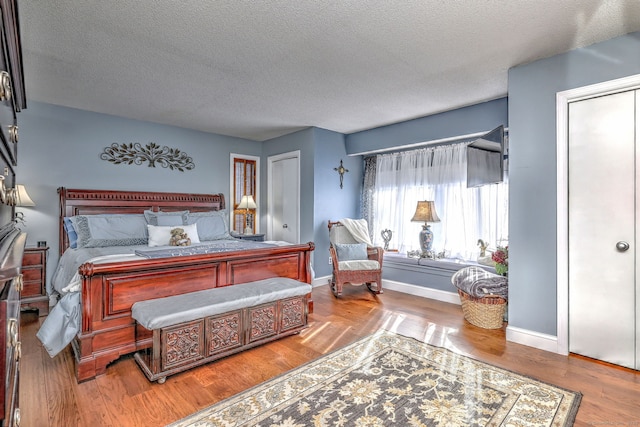 bedroom featuring a textured ceiling, wood finished floors, and baseboards