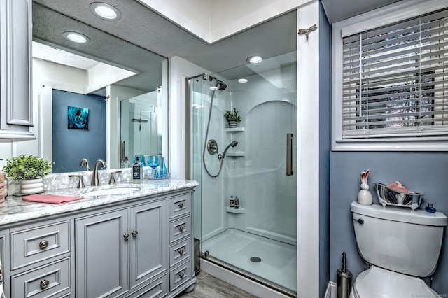 bathroom featuring toilet, a stall shower, recessed lighting, and vanity