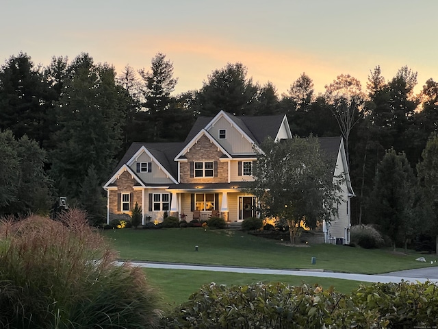 view of front facade featuring stone siding, board and batten siding, and a front yard