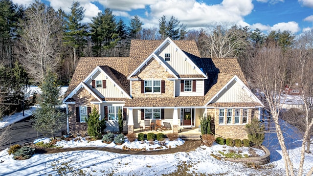 craftsman house featuring stone siding, a shingled roof, and board and batten siding