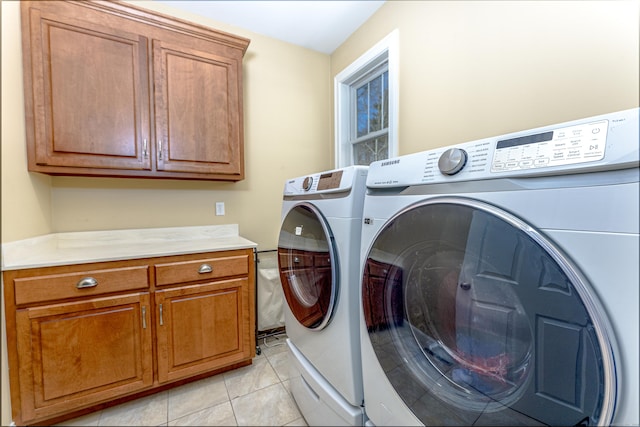 washroom featuring cabinet space, washing machine and clothes dryer, and light tile patterned floors