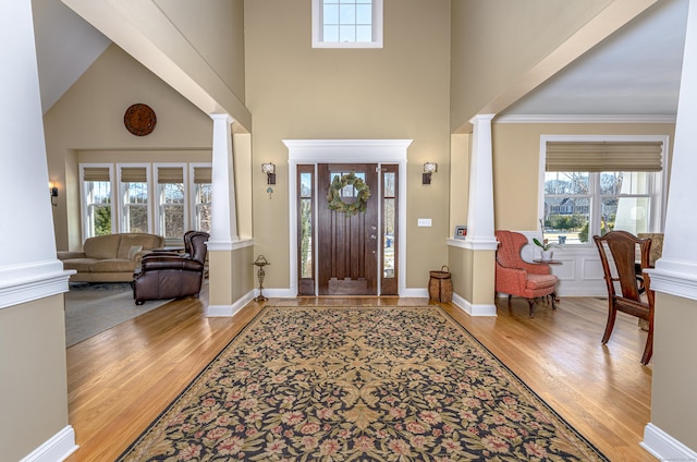 entrance foyer featuring a wealth of natural light, decorative columns, and wood finished floors