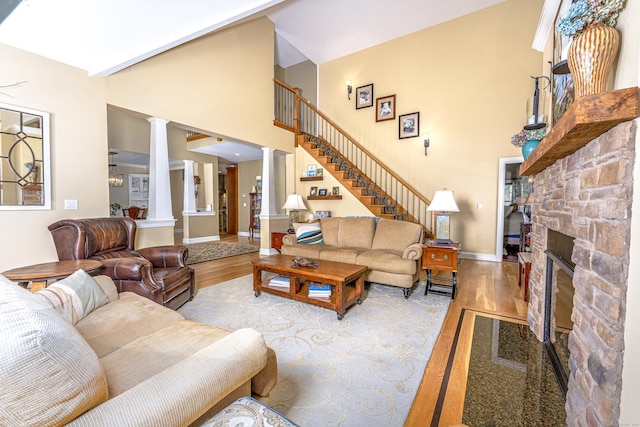 living room with a fireplace, decorative columns, stairway, a high ceiling, and wood finished floors