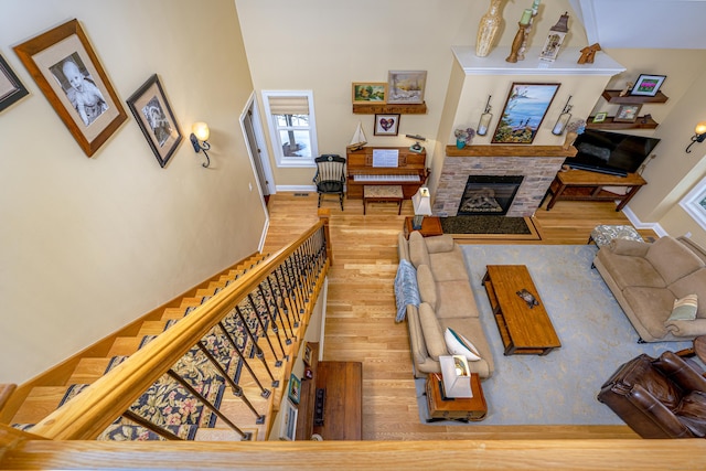 living room with a stone fireplace, baseboards, and wood finished floors