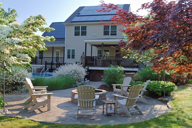 rear view of property featuring an outdoor fire pit, roof mounted solar panels, and a patio