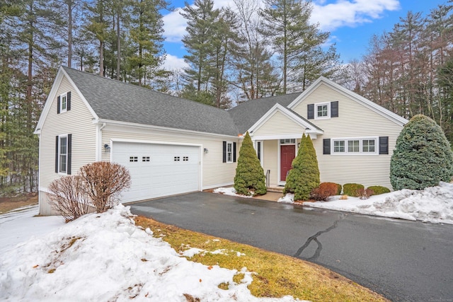 traditional home with a garage, aphalt driveway, and roof with shingles