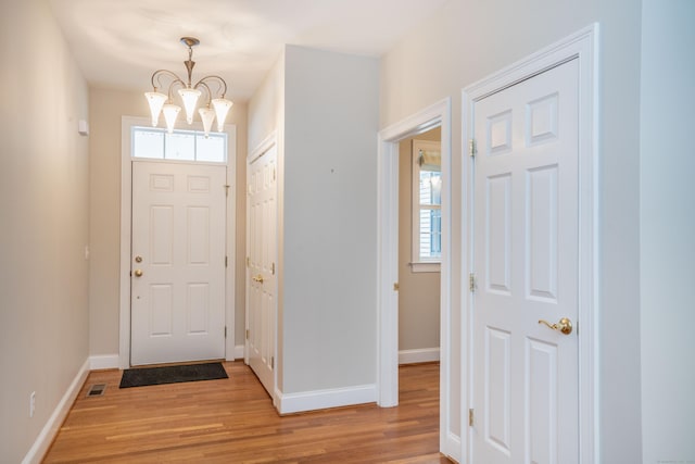 entrance foyer featuring a chandelier, light wood finished floors, visible vents, and baseboards