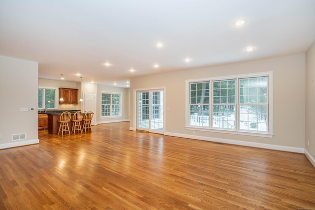 unfurnished living room featuring baseboards, light wood-type flooring, visible vents, and recessed lighting