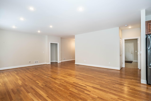 empty room with light wood-style floors, recessed lighting, visible vents, and baseboards