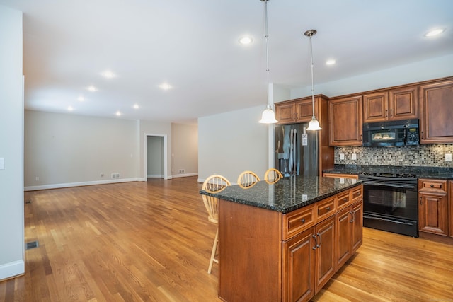 kitchen featuring a center island, light wood finished floors, visible vents, decorative backsplash, and black appliances