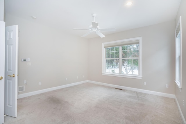 unfurnished room featuring baseboards, a ceiling fan, visible vents, and light colored carpet