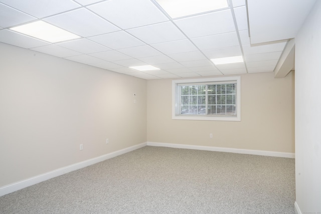 unfurnished room with a paneled ceiling, carpet, and baseboards