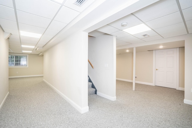 basement with a paneled ceiling, carpet, and baseboards