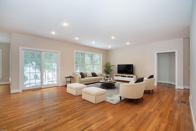 living area featuring light wood-style floors, baseboards, visible vents, and recessed lighting