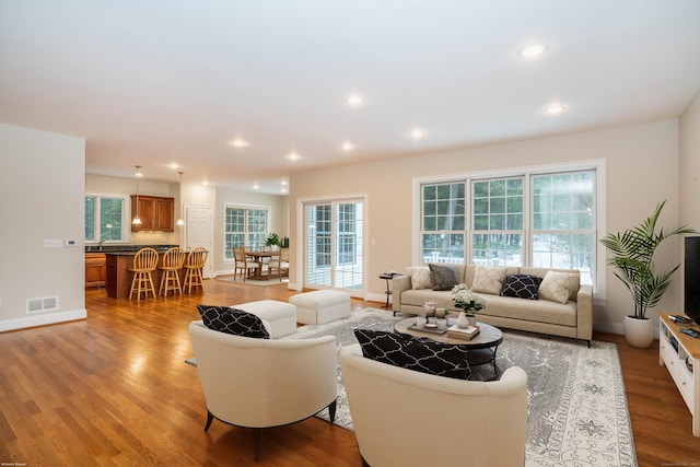 living area featuring baseboards, visible vents, wood finished floors, and recessed lighting