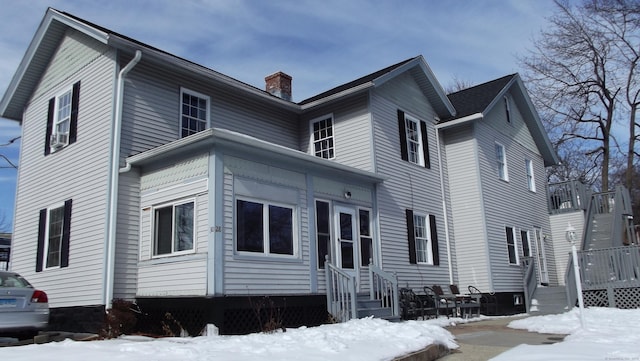 snow covered property featuring entry steps and a chimney