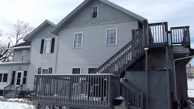 snow covered property featuring stairs and a deck