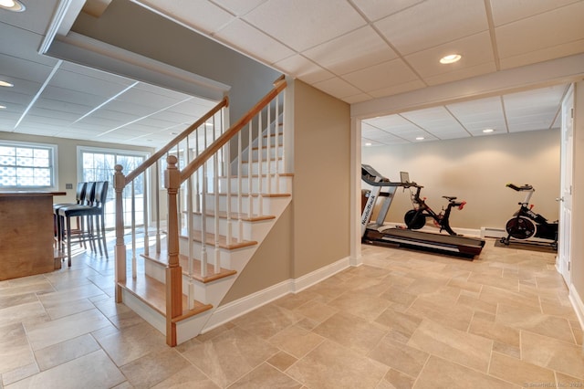 workout area with a baseboard heating unit, a paneled ceiling, baseboards, and recessed lighting