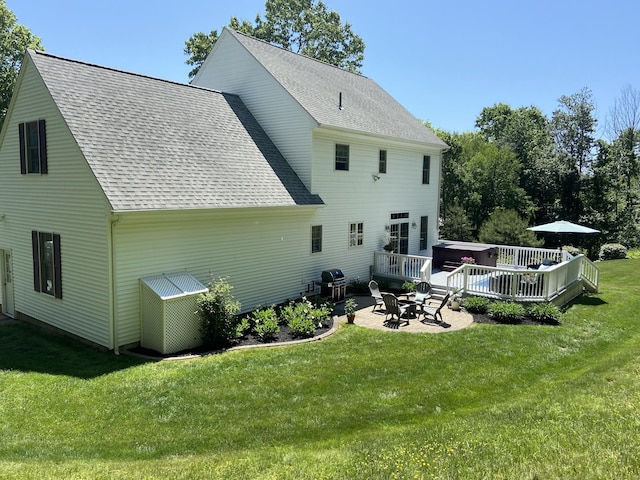 back of property with a patio area, roof with shingles, and a yard