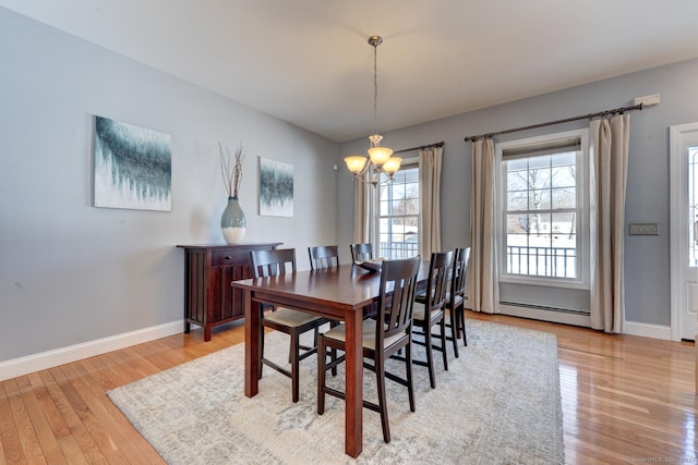 dining area featuring baseboards, light wood-style floors, baseboard heating, and an inviting chandelier