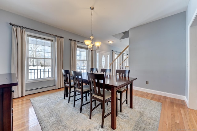 dining area with baseboard heating, an inviting chandelier, light wood-style floors, baseboards, and stairs