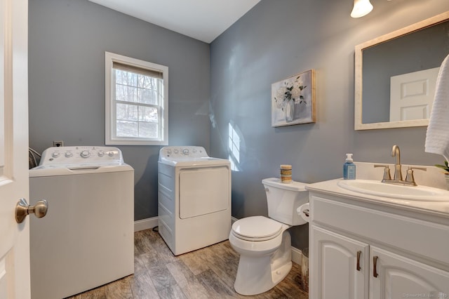 half bathroom with baseboards, toilet, wood finished floors, independent washer and dryer, and vanity