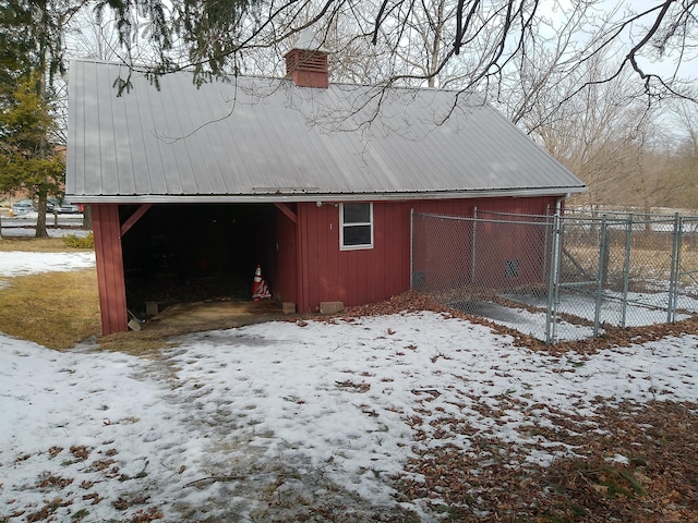 snow covered structure with an outdoor structure and fence