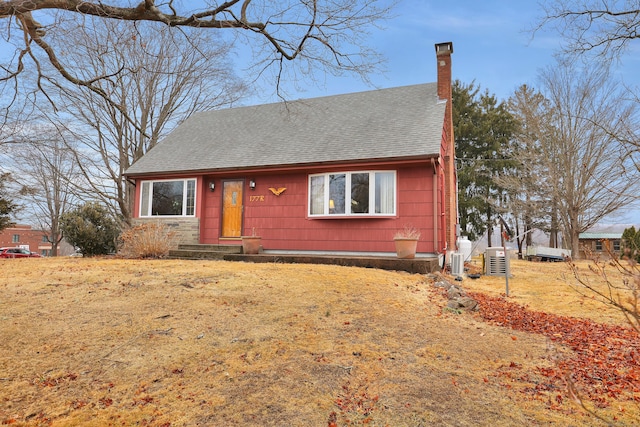 view of front facade with a shingled roof and a chimney