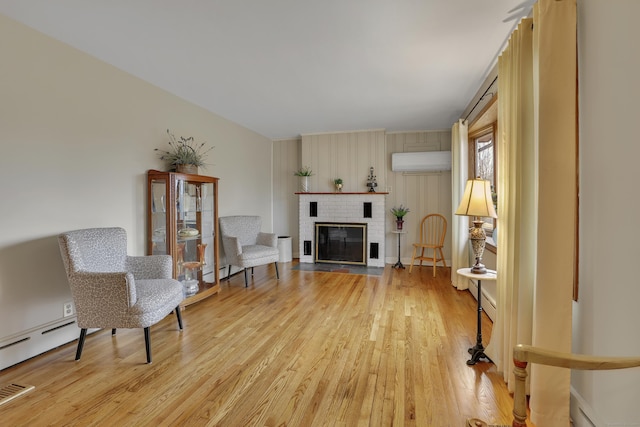 living area featuring light wood-style flooring, a fireplace, and an AC wall unit