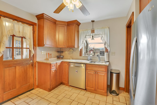 kitchen featuring light stone counters, tasteful backsplash, appliances with stainless steel finishes, a ceiling fan, and a sink