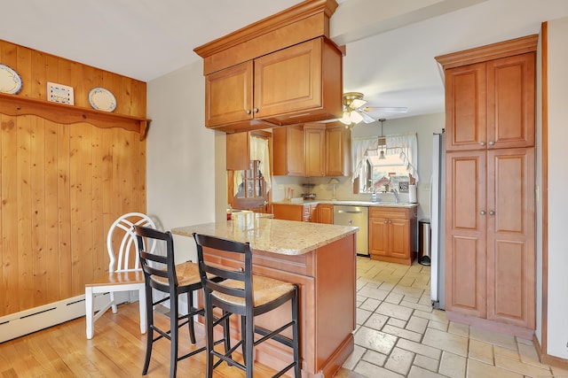 kitchen with light stone counters, ceiling fan, dishwasher, a peninsula, and a kitchen breakfast bar