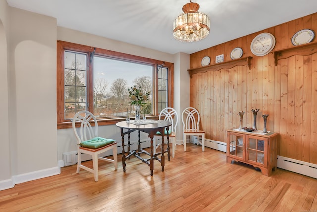 dining area featuring light wood finished floors, a baseboard heating unit, and a notable chandelier