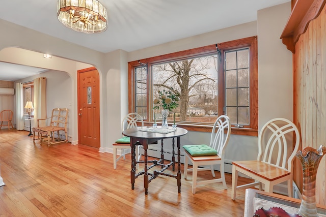 dining area featuring baseboards, arched walkways, a chandelier, and wood finished floors