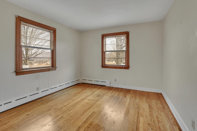 spare room with a baseboard heating unit, baseboards, and wood finished floors