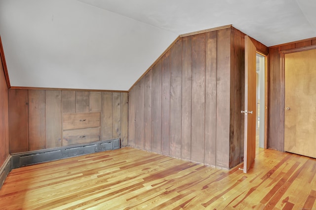 bonus room featuring lofted ceiling, hardwood / wood-style flooring, a baseboard radiator, and wooden walls