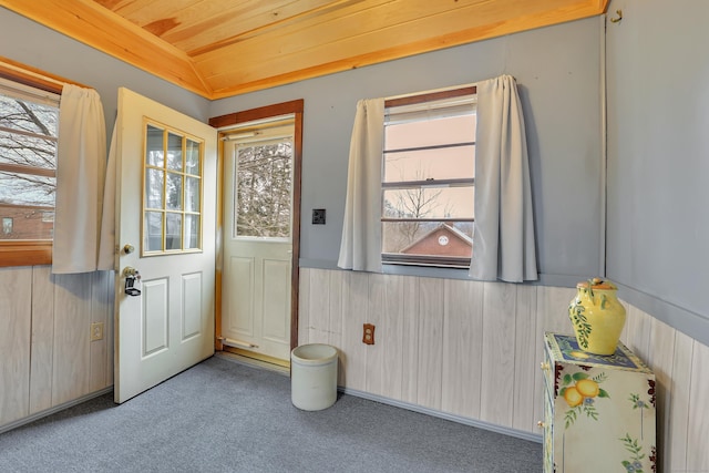 doorway to outside featuring lofted ceiling, wooden ceiling, carpet, and wood walls