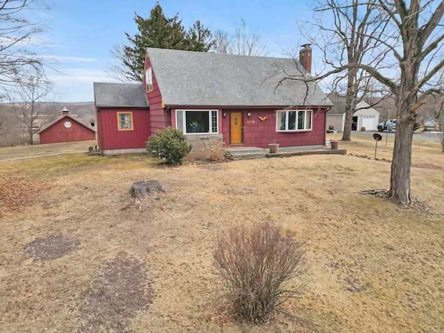 view of front facade featuring roof with shingles and a chimney