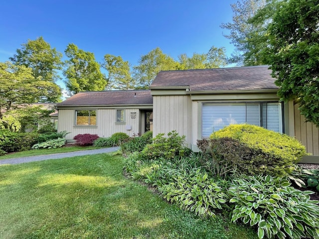 view of front of home with a garage, a shingled roof, and a front yard