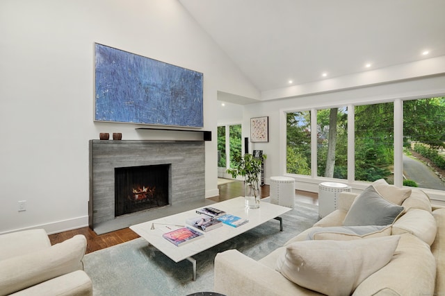 living area with a fireplace with flush hearth, recessed lighting, high vaulted ceiling, and wood finished floors