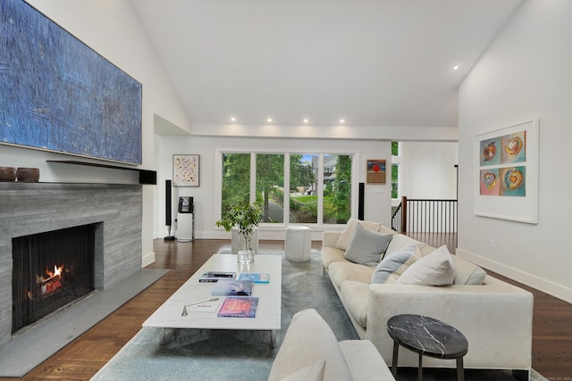 living area featuring a warm lit fireplace, high vaulted ceiling, recessed lighting, baseboards, and dark wood finished floors