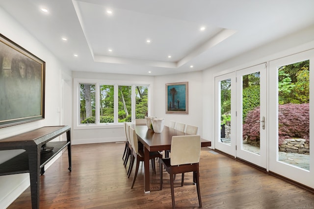 dining area with dark wood-style floors, a raised ceiling, and recessed lighting