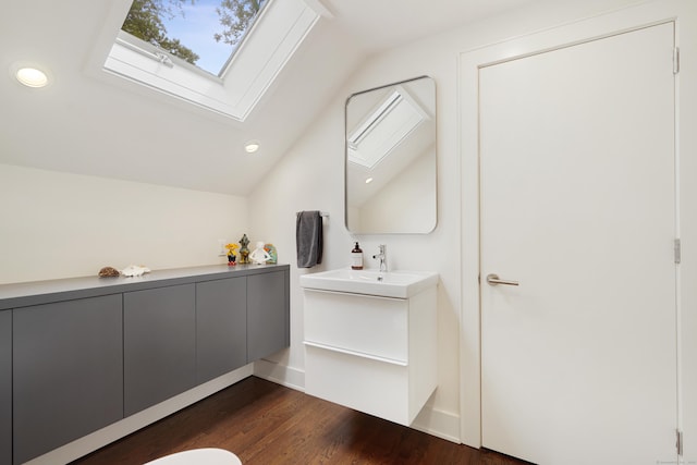 bathroom with lofted ceiling with skylight, recessed lighting, vanity, and wood finished floors